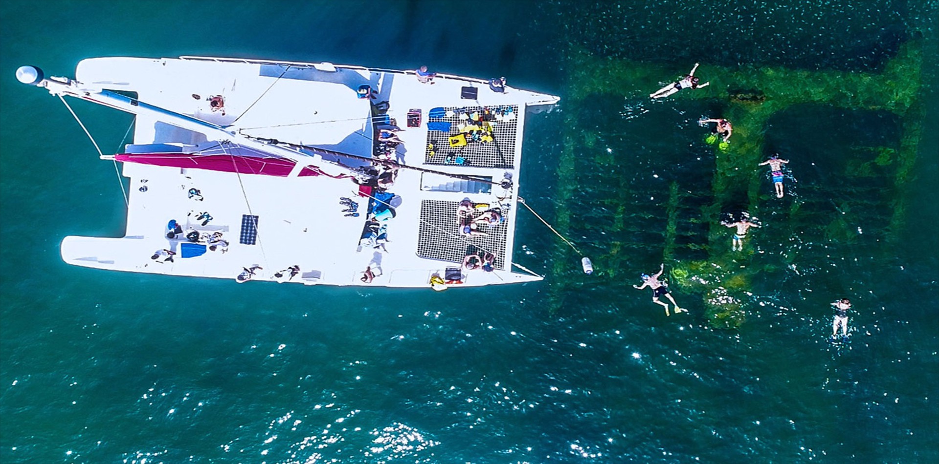 Aerial view of a catamaran with swimmers in turquoise water